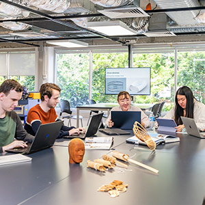 group of students sitting around a table working on laptops