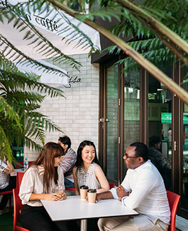 Group sitting outside with coffees chatting