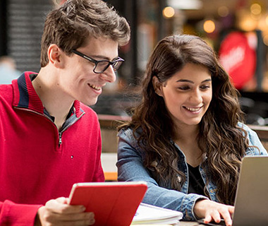 students sitting outside working on laptop