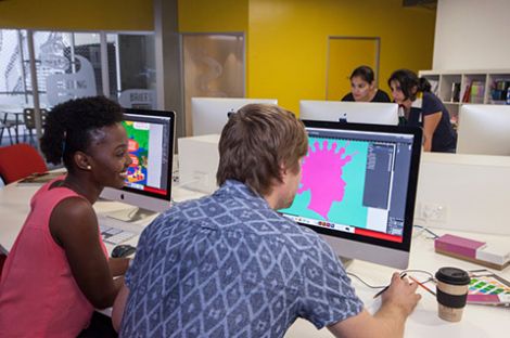 Two students staring at a computer monitor that displays a design