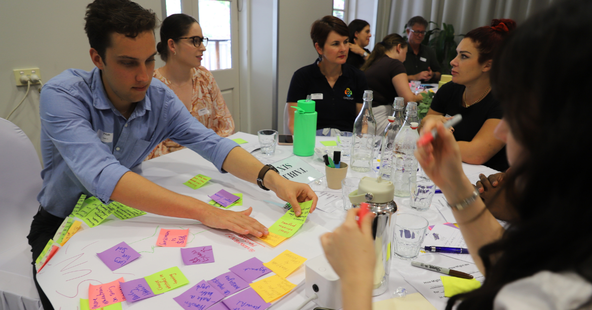 A table of people putting post-it's on a butchers paper.