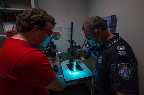 Two men wearing masks staring down at equipment