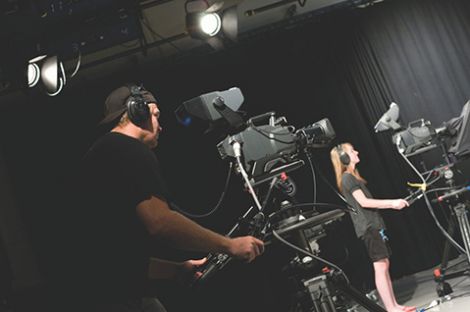 Two people holding tv cameras in a studio