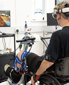 Participant using rehabilitation equipment with neural monitoring in a lab.