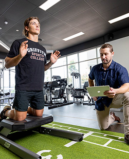 Athlete performing an exercise while a trainer observes and records data.