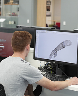 Student developing a robotic arm on a computer