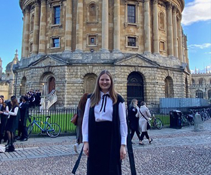 Picutre of woman with blonde hair in front of a old building at oxford