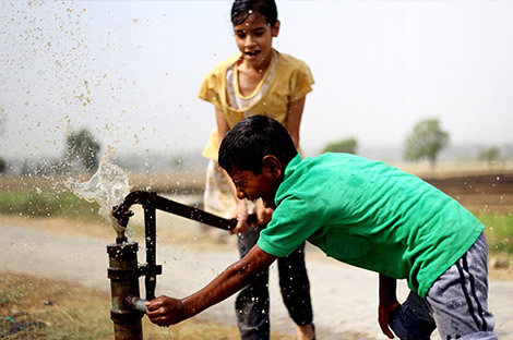 Rural children drinking water outdoor in nature.