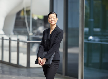 Jennifer Cheung in front of office building, carrying a laptop