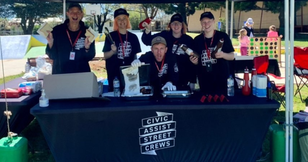 Five people standing behind a table with the sigh 'Civic Assist Street Crews'.